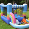 Kids playing in ball pit and bouncing inside colorful rainbow inflatable rental near Portland Oregon