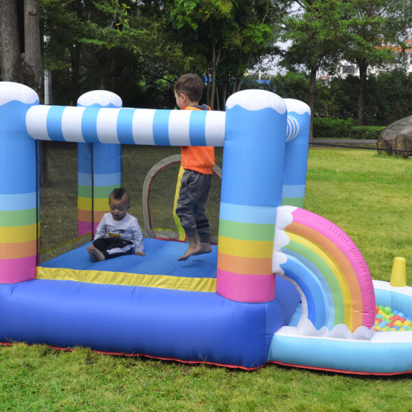 Two toddlers jumping inside rainbow bounce house with ball pit at backyard party in Beaverton