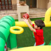 Boy playing basketball hoop inside dinosaur bounce house rental - fun party activity for kids
