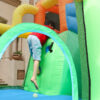 Boy climbing through tunnel entrance inside dino themed bounce house with slide rental