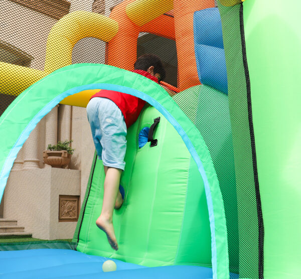 Boy climbing through tunnel entrance inside dino themed bounce house with slide rental