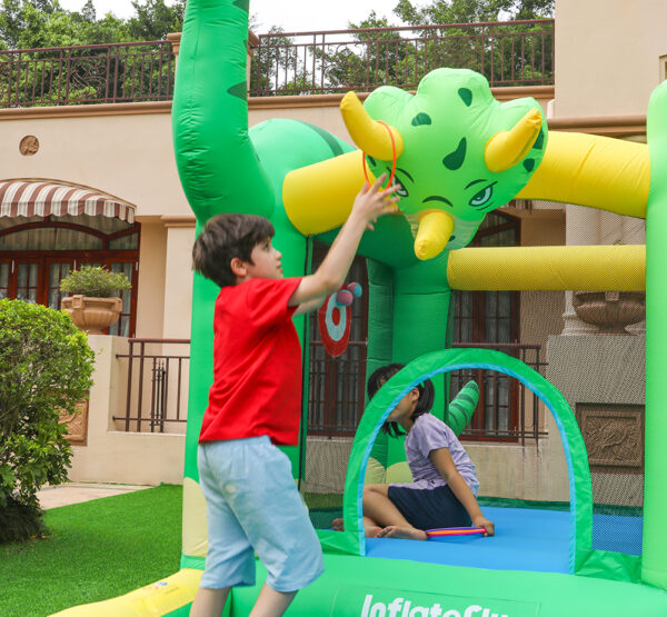 Kids playing with inflatable triceratops decoration on Dino Kingdom bounce house rental in Beaverton Oregon