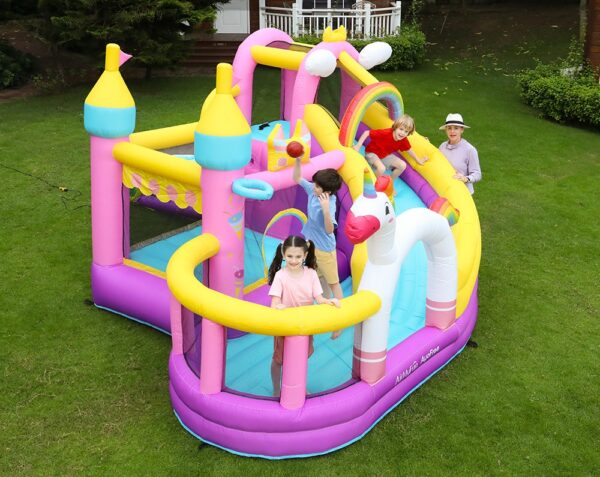 Kids bouncing and playing on dreamy unicorn castle bounce house combo with slide and ball pit in backyard - Portland Oregon rental