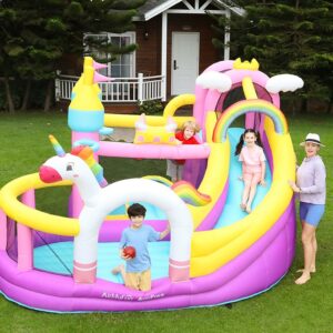 Kids playing on colorful unicorn rainbow bounce house with slide in backyard - bounce house rental Beaverton Oregon