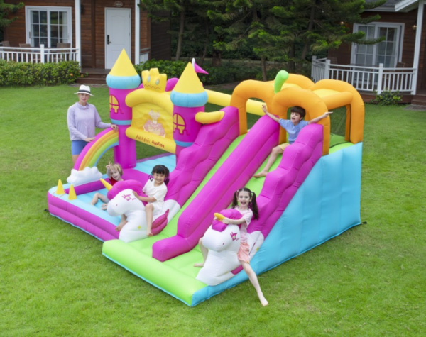 Children sliding down double slides on princess unicorn bounce house combo rental in Portland Oregon