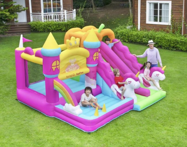 Kids playing on pink princess unicorn bounce house with double slide in backyard - bounce house rental Beaverton Oregon