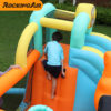Boy climbing up the padded climbing wall inside music themed bounce house with slide rental
